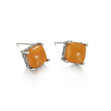 Square amber stud earrings set in textured silver prong settings on white background