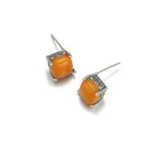 Pair of orange jade stud earrings with intricate silver metal settings on white background