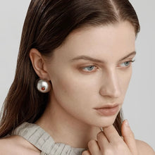 Close-up of woman with blue eyes wearing silver round stud earrings with small red accents
