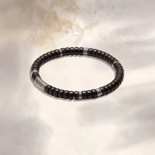 Black beaded bracelet with silver accents on a light textured background