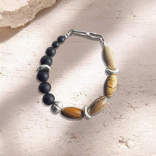 Beaded bracelet with black matte and natural stone beads on textured beige surface