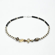 Delicate beaded necklace with black cubes, white pearls, and mixed glass beads on white background