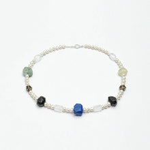 Delicate pearl necklace with multi-colored gemstone beads and silver clasp on white background