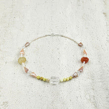 Handcrafted necklace with mixed beads including pearls, jasper, quartz, and irregular shaped stones on textured surface