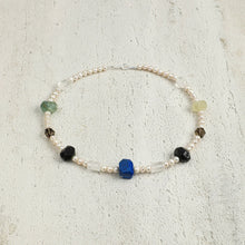 Elegant beaded necklace with pearl and multicolored gemstone beads on textured surface