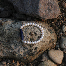 Elegant pearl bracelet with blue gemstone centerpiece on natural rocky surface