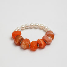 Beaded bracelet with white pearls and large faceted orange agate stones on white background