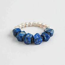 Bracelet with large blue lapis lazuli stones and white pearls on a light background