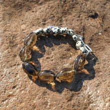 Dalmation jasper and amber glass bead bracelet on a textured brown stone surface