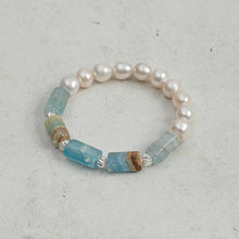 Bracelet with irregular white pearls and rectangular blue and brown gemstone beads on gray surface