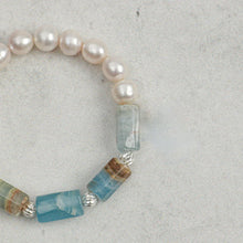 Close-up of a bracelet with pink pearls and blue polished stone beads on a gray background