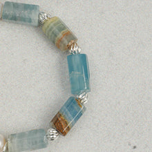 Close-up of aquamarine gemstone beads with silver spacer beads on a light background