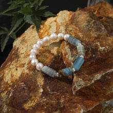 Elegant beaded bracelet with pearls and blue-green agate stones on rustic rock