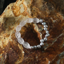 Bracelet with clear carved beads and silver pearls on textured brown rock background