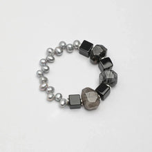 Bracelet with gray pearls, black square beads, and smoky quartz stones on white background