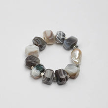 Chunky bracelet with polished gray and beige stones and a single large pearl bead