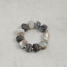 Bracelet with irregular gray and white agate stones and a single large pearl on a light gray background