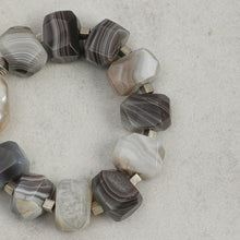 Close-up of faceted grey and white agate bead bracelet on light grey background