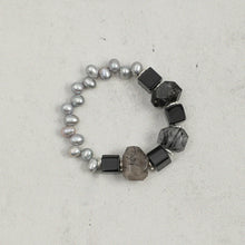 Elegant bracelet with grey pearls, black square beads, and faceted smoky quartz stones on gray background