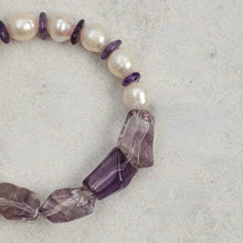 Close-up of a bracelet with white pearls and purple amethyst beads on a light surface