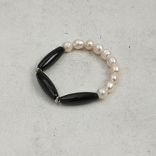 Black and white pearl bracelet on light gray textured background