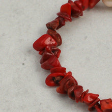 Close-up of red coral chip bead necklace on light gray surface