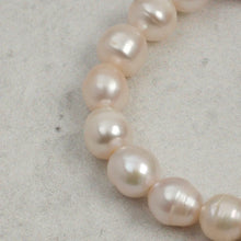 Close-up of natural white freshwater pearl necklace on light textured surface