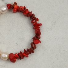 Close-up of red coral chip and pearl bead necklace on gray surface