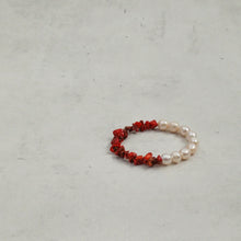 Red coral and white pearl beaded bracelet on light gray textured background