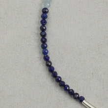 Close-up of polished deep blue faceted beads on a light grey textured background