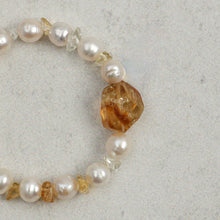 Close-up of a pearl and citrine gemstone bracelet on a light textured background