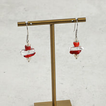 Red and clear beaded drop earrings with pearl detail on brass display stand