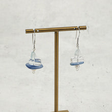 Handcrafted dangle earrings with blue, clear, and white beads on brass stand