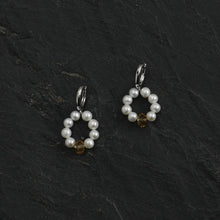 Elegant pearl hoop earrings with amber centerpiece on dark textured slate background