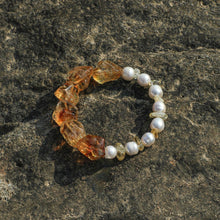 Bracelet with large amber stones and white pearls on textured natural rock surface
