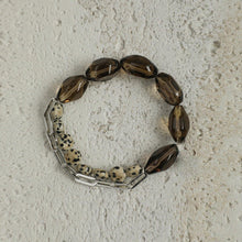 Bracelet with smoky brown beads, speckled stone beads, and silver chain links on textured background