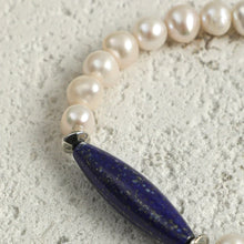 Close-up of pearl bracelet with oval blue lapis lazuli stone on textured surface