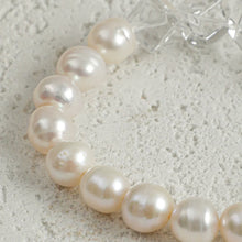 Close-up of a white pearl necklace on textured concrete surface with clear star-shaped beads