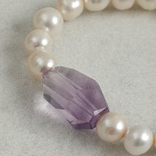 Close-up of pearl necklace with large faceted amethyst gemstone centerpiece on gray surface