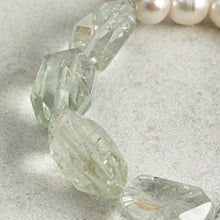 Close-up of translucent faceted crystal beads with a strand of pearls on light textured surface