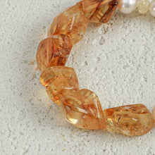 Close-up of polished amber gemstone beads on textured light grey surface