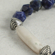 Close-up of blue gemstone beads and silver-accented white stone bead necklace on light surface