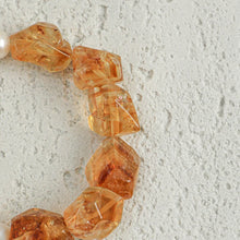 Close-up of translucent irregular amber beads on textured light gray surface