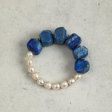 Bracelet with irregular blue stones and white pearls on a light grey surface