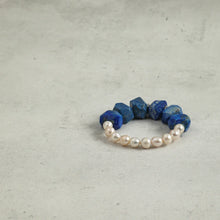 Elegant bracelet with blue lapis lazuli stones and white pearls on a gray concrete surface