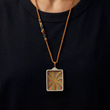 Tibetan Echo colorful swirl pattern pendant on braided brown cord necklace worn over black shirt
