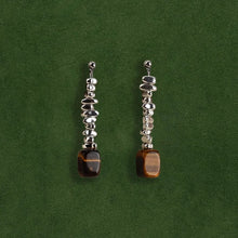 Elegant silver drop earrings with irregular shiny beads and rectangular tiger eye stones on dark green background