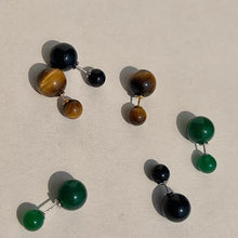Set of double-sided stud earrings in tiger eye, black, and green colors on beige background
