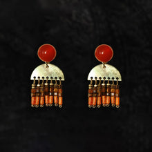 Pair of gold-tone earrings with red round tops, half-circle metal hangings, and orange bead fringe