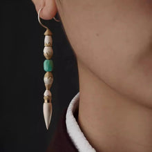 close-up of long bohemian earring with white, gold, and turquoise beads on female ear